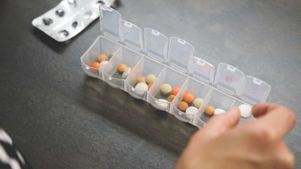patient adding medications to pill container
