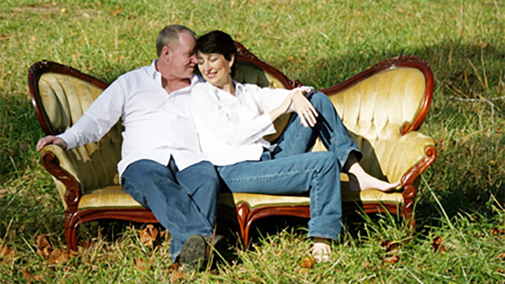 Robin and Rick sitting together on a couch outdoors