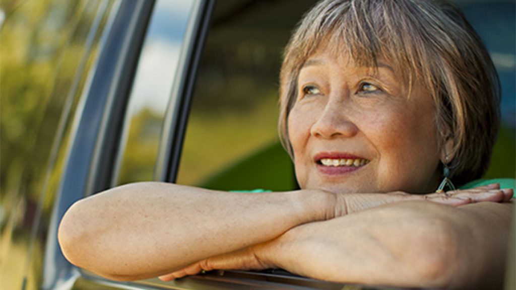 Elderly woman looking outside the window while inside a vehicle